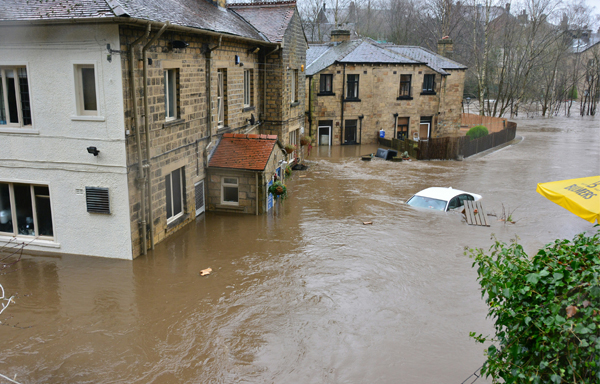 Image of a river, flooded engulfing roads, a pub, and private proterty. Flood caused by climate chage